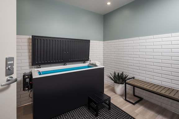 A modern bathroom with a black tub and a bench.