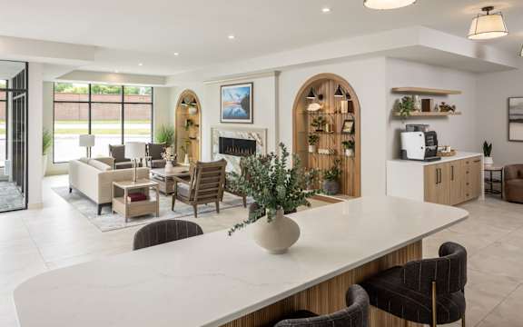 A modern living room with a large white table and brown chairs.