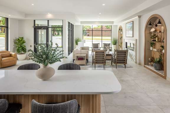 A modern dining room with a marble table and grey chairs.