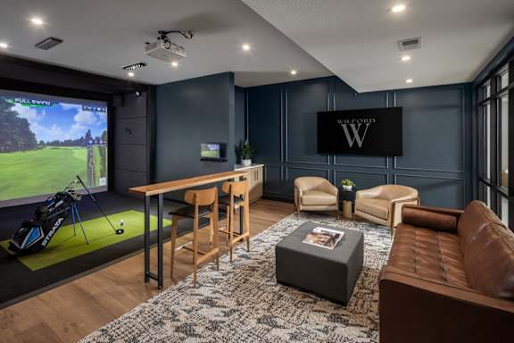 A modern living room with a golf simulator and a large TV.