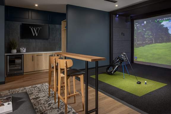 A room with a golf simulator and a bar area.