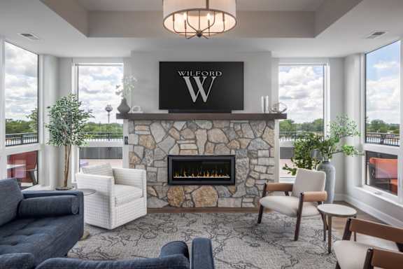A living room with a stone fireplace and a large window.
