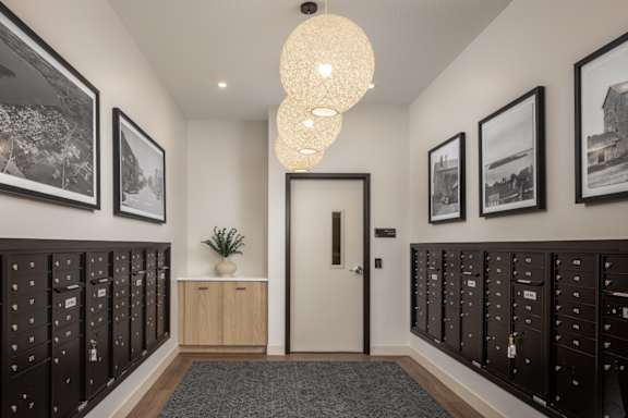 A hallway with a white door, black lockers on both sides, and pictures on the wall.