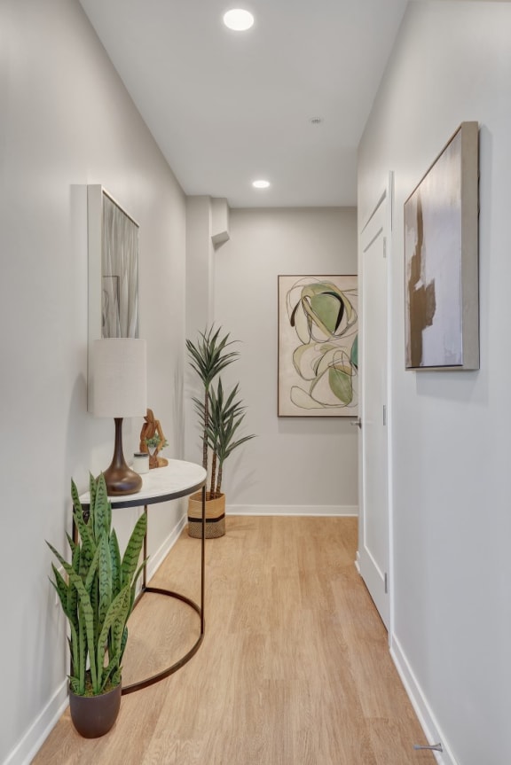 a hallway with white walls and a white table with a lamp on it