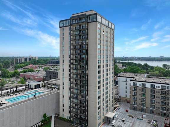 an aerial view of a tall building with a pool in front of it