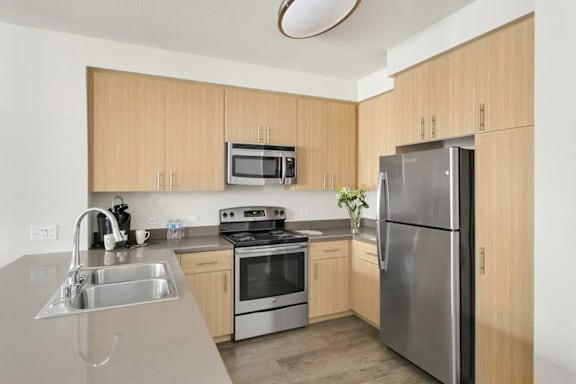 A kitchen with wooden cabinets and stainless steel appliances.at Cirrus Redwood City, Redwood City, 94061