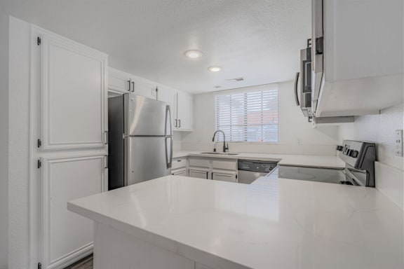 a kitchen with a white counter top and a refrigerator  at The Resort at Encinitas Luxury Apartment Homes, California