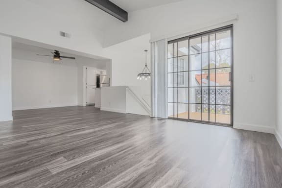 an empty living room with a large window and a staircase  at The Resort at Encinitas Luxury Apartment Homes, Encinitas, CA