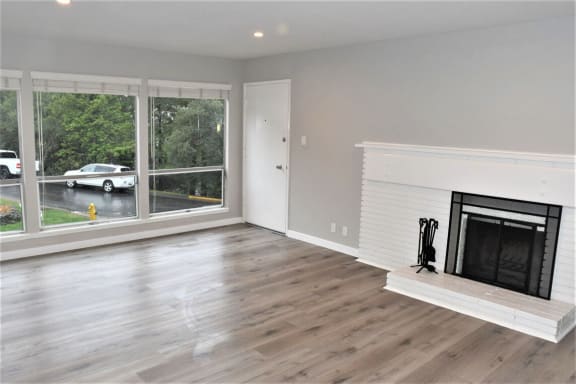 a living room with a fireplace and a large window at Trailhead Apartments at Tam Junction, Mill Valley, CA