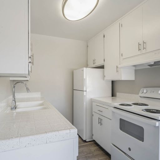 a kitchen with a stove and a sink and a refrigerator at The Arches Apartments, El Cajon, 92021