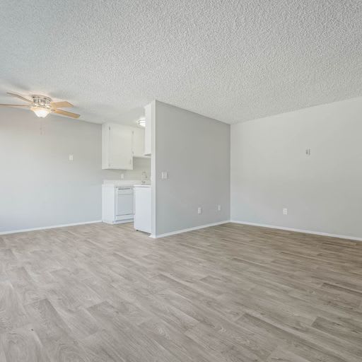an empty living room and kitchen with a ceiling fan at The Arches Apartments, El Cajon California