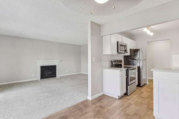 an empty living room with a kitchen and a fireplace at Summerwood Apartments, California