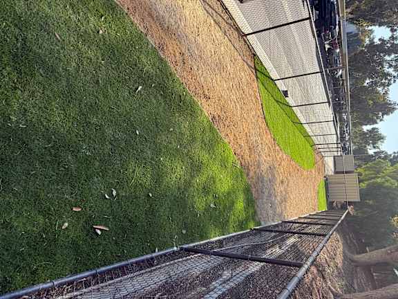 A grassy area with a fence and a building in the background.