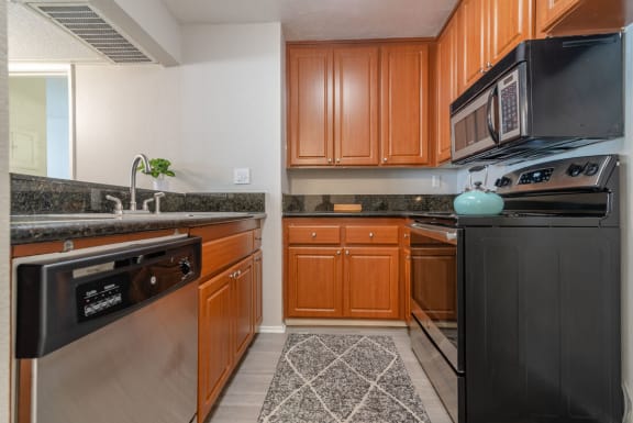 a kitchen with stainless steel appliances and wooden cabinets at City View Apartments at Warner Center, California