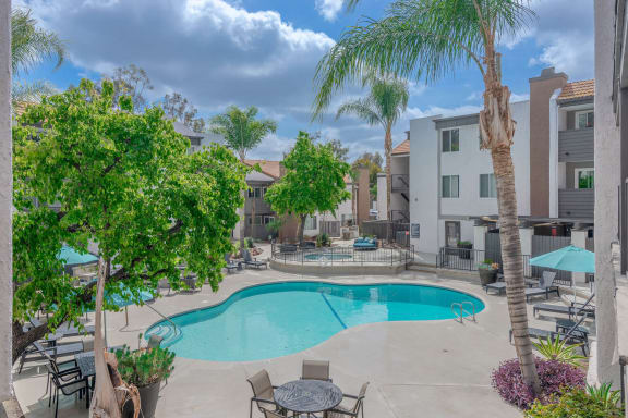 a swimming pool with tables and chairs and palm trees at City View Apartments at Warner Center, Woodland Hills California
