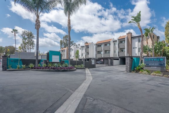 an empty parking lot in front of a building with palm trees at City View Apartments at Warner Center, Woodland Hills, CA