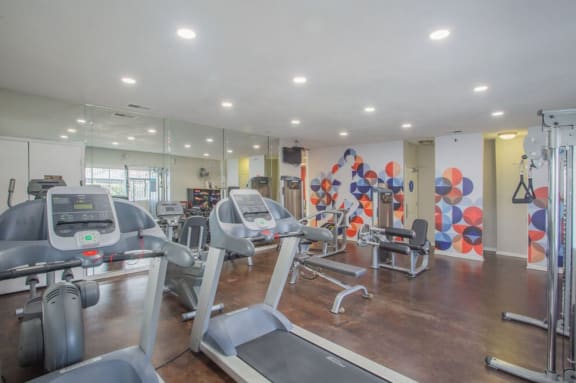 a gym with cardio equipment and mirrors in a building at Sunnyvale Crossings Apartments, LLC, Sunnyvale, CA 94087