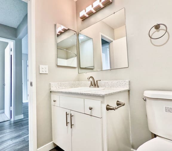 a bathroom with a sink and a mirrorat The Arches Apartments, LLC, El Cajon, CA