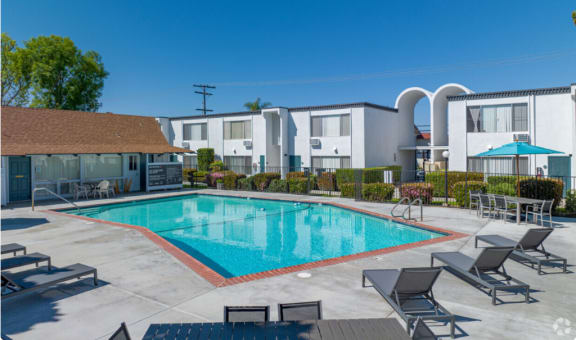 a swimming pool with chairs around it in front of a buildingat The Arches Apartments, LLC, El Cajon California