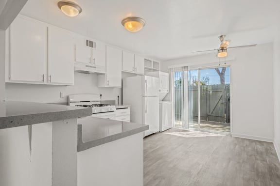 a white kitchen with white cabinets and a sliding glass door at Ocean Villas, Oxnard, CA