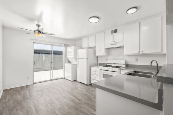a kitchen with white cabinets and white appliances and a sliding glass door at Ocean Villas, California, 93033
