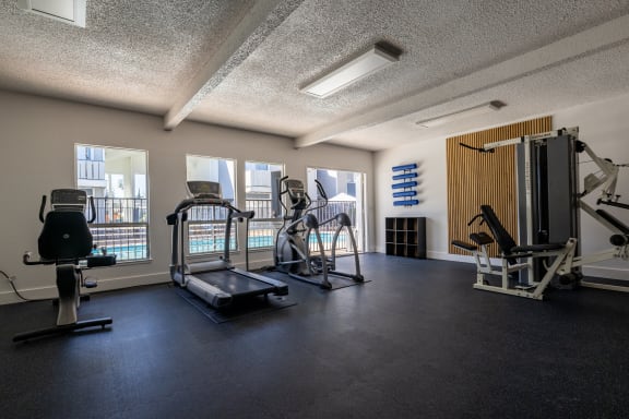 a gym with weights and cardio equipment in a building with windows at Campbell West Apartments, California 95008
