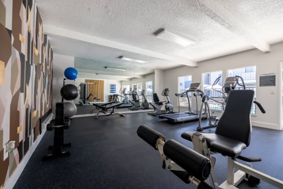 a gym with weights and other exercise equipments in a room with a large window at Campbell West Apartments, Campbell, 95008