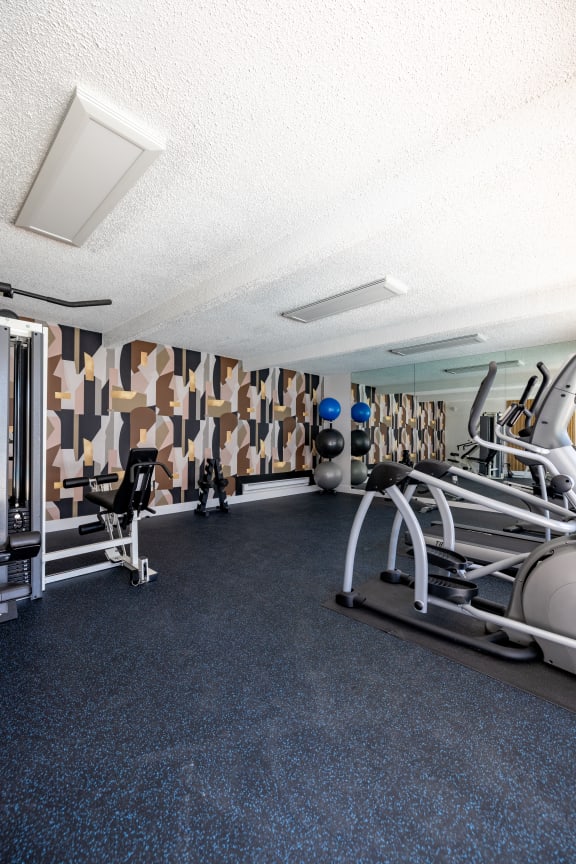 a gym with weights and other equipment on the floor at Campbell West Apartments, Campbell, California