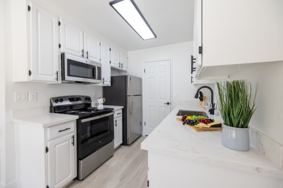 a kitchen with white cabinets and stainless steel appliances and a counter top with a sink at Campbell West Apartments, Campbell, CA