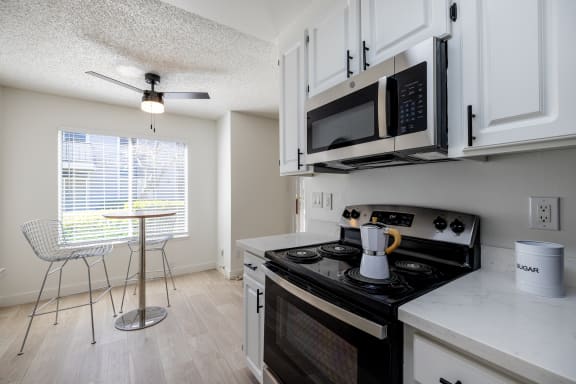 a kitchen with a stove and microwave and a table with a chair at Campbell West Apartments, Campbell, 95008