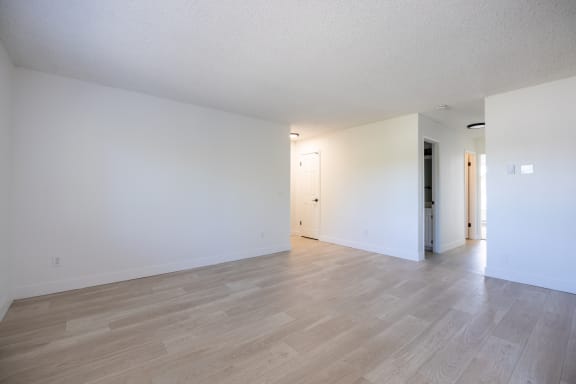 the living room and dining room of an apartment with white walls and wood floors at Campbell West Apartments, Campbell