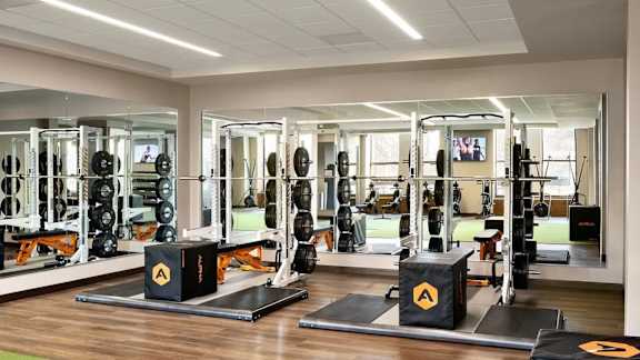 A gym with a variety of equipment including weightlifting machines and a television.