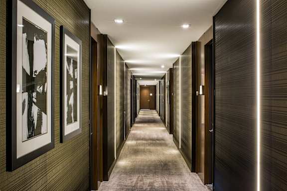 A long hallway with a series of doors on the right and framed pictures on the left. at SKY Apartments, New York, NY