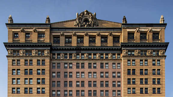 A large building with a statue on top of it at One West,New York, NY.