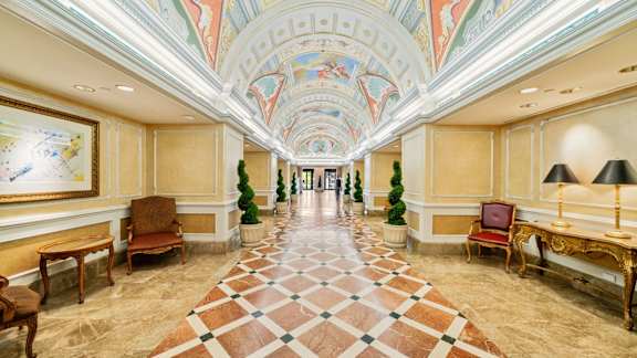 A long hallway with a checkered floor and chairs on either side at One West, New York.