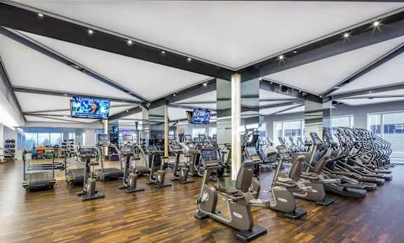 a gym with cardio machines and weights on a wooden floor at SKY Apartments, New York