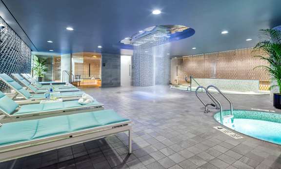 a spa with a jacuzzi and a pool in a room with chairs at SKY Apartments, New York 10036