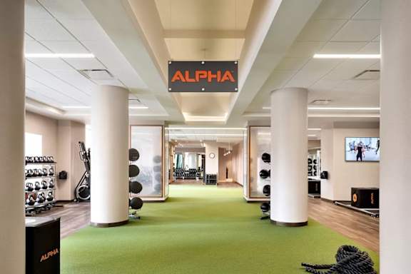 A gym with a green floor and a sign that says Alpha. at One West, New York, NY,10004