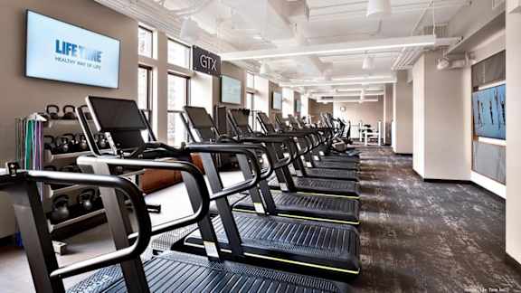 A gym with treadmills and a sign that says LIFE Time. at One West,  New York,10004