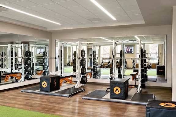 A gym with a variety of equipment including weightlifting machines and a green mat. at One West,New York, NY