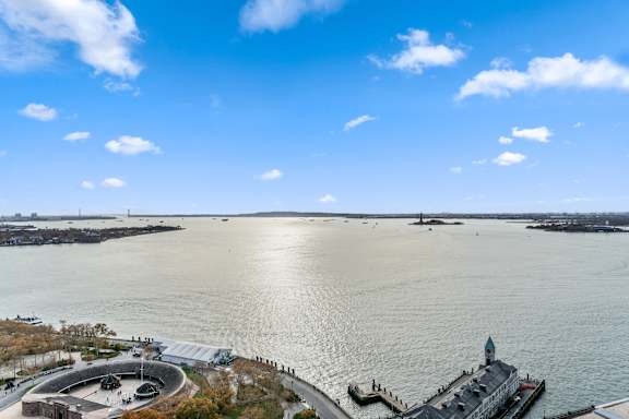 A large body of water with a building and a boat docked at the pier at One West,New York, NY.