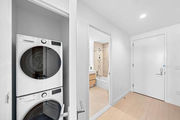 A white washing machine and dryer in a small laundry room at One West, New York, New York.