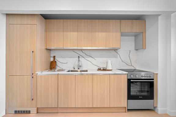A kitchen with wooden cabinets and a white countertop at One West,New York, NY.