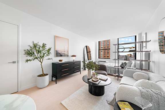 A living room with a white couch, a coffee table, and a plant. at One West, New York, New York