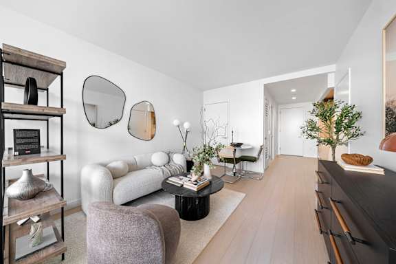 A living room with a grey armchair and a black coffee table at One West,New York, NY.