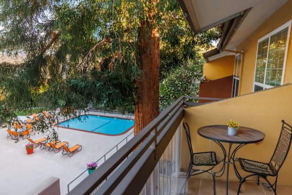 A patio with a table and chairs overlooks a pool.