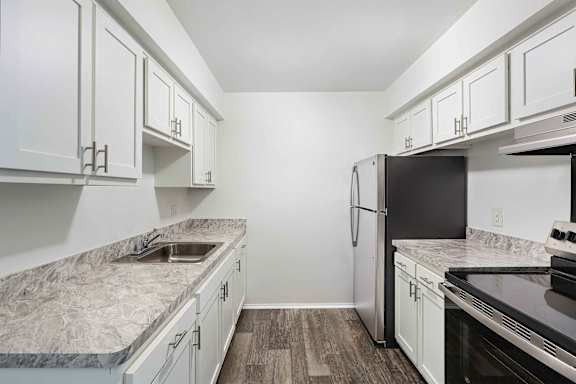 A kitchen with white cabinets and a marble countertop.