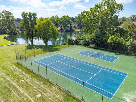 A tennis court surrounded by a fence and trees.
