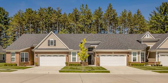 A house with a grey roof and a yellow tree in front.