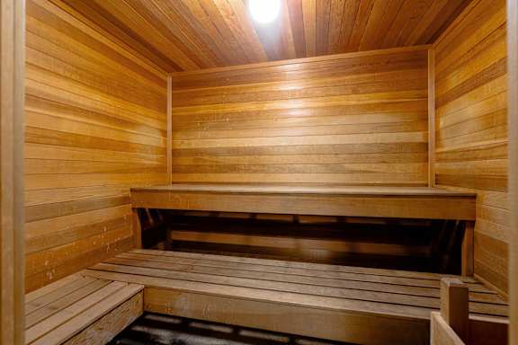 Interior of a wooden sauna with wooden benches and warm lighting.